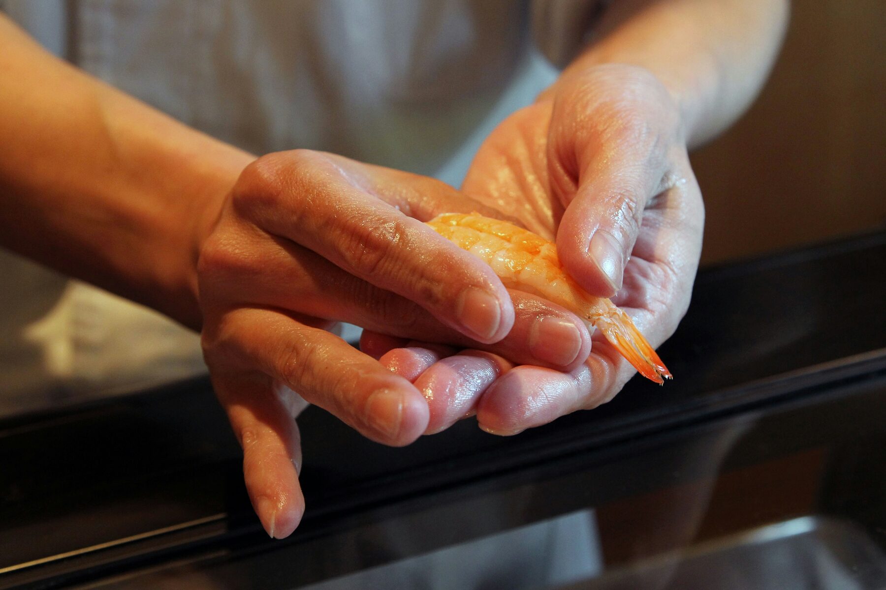 Le mani dello chef formano il nigiri