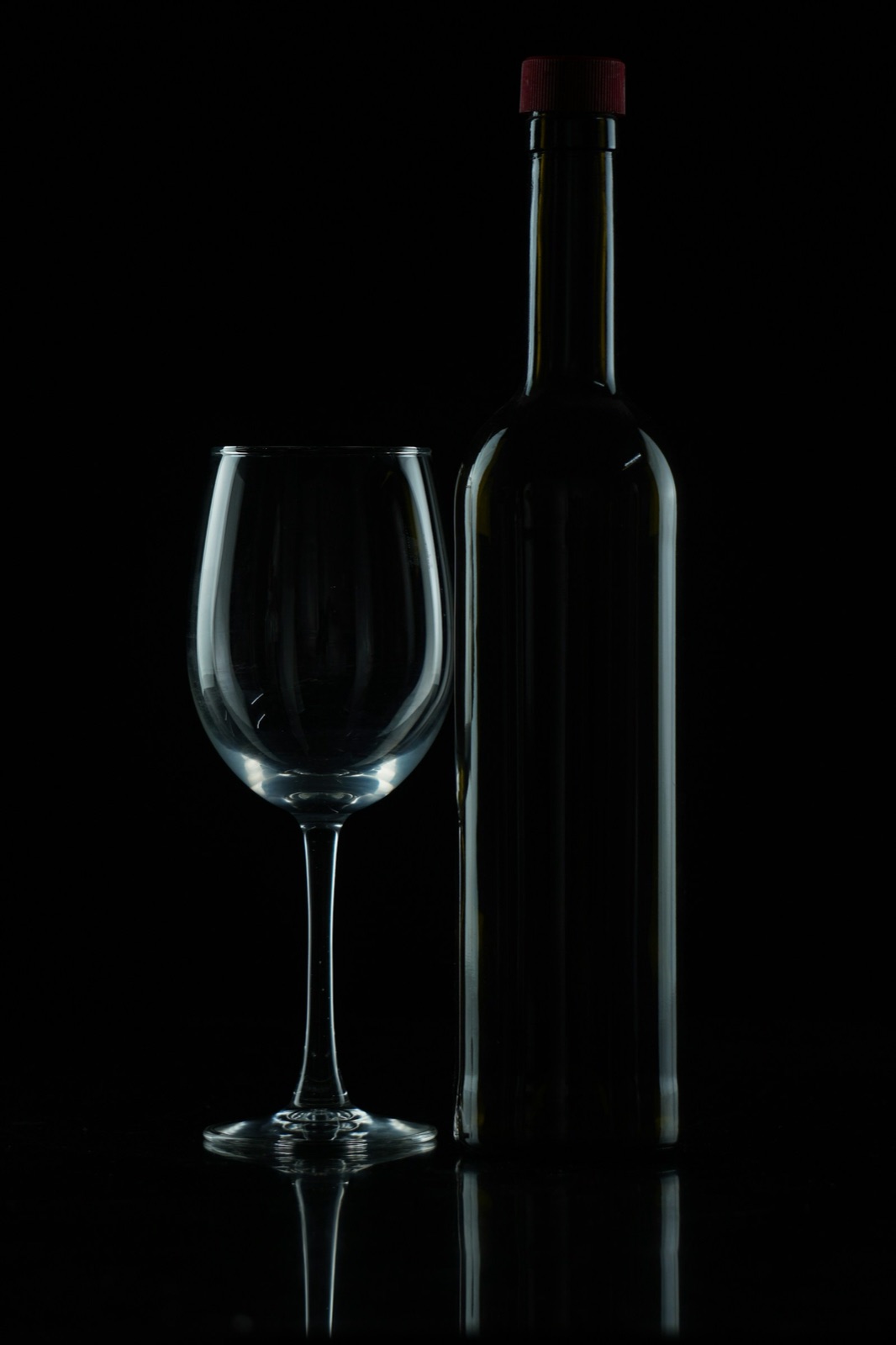 Una bottiglia di vino e un calice nella penombra